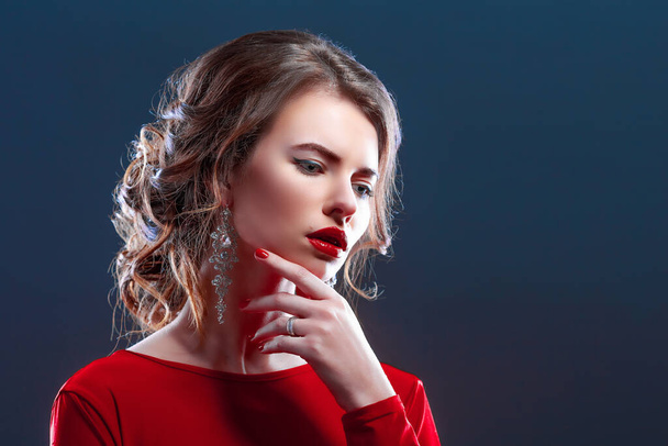 Woman with makeup, hairstyle waering red dress posing with glass of vine over dark background, isolate - Zdjęcie, obraz