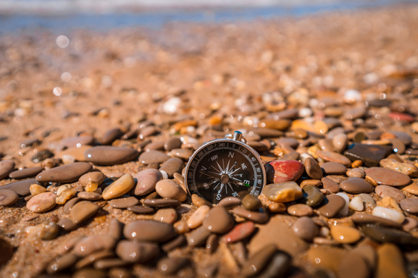 Hintergrundbild des Kompasses, der auf kleinen Kieselsteinen am Strand mit Meerblick liegt, Reisekonzept - Foto, Bild