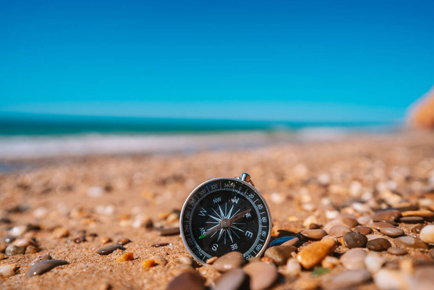 Imagem de fundo da bússola deitada em pequenos seixos da praia com vista para o mar, conceito de viagem - Foto, Imagem