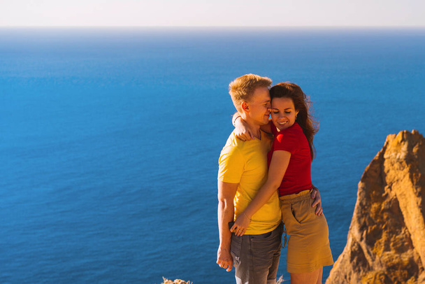 幸せな若いカップルの男性と女性の岬の崖の端に、家族の若者の旅行の概念を受け入れる - 写真・画像