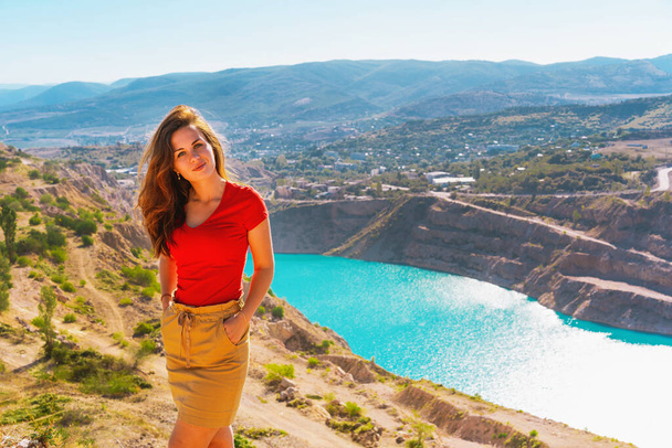  Une belle femme en vêtements rouges se dresse sur une carrière avec un lac azur, carrière en Crimée est une attraction touristique naturelle - Photo, image