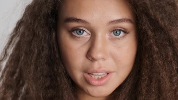 Nahaufnahme schöne brünette Mädchen sinnlich öffnende Augen und Lächeln in der Kamera isoliert über weißem Hintergrund - Filmmaterial, Video