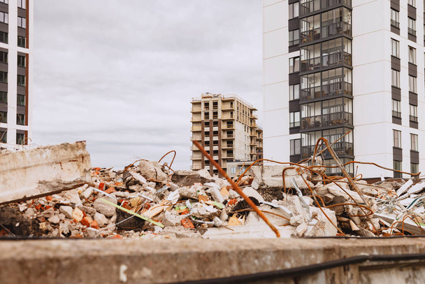 Pile of rubble of destroyed building against background of new and unfinished residential buildings. Concept of housing renovation in metropolis. Building background with copyright space - 写真・画像