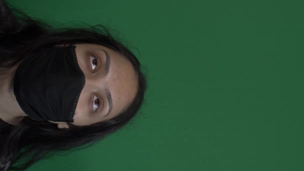 Jovem mulher asiática do Reino Unido vestindo máscara facial preta olhando para cima. Vídeo Vertical, Tela Verde - Filmagem, Vídeo