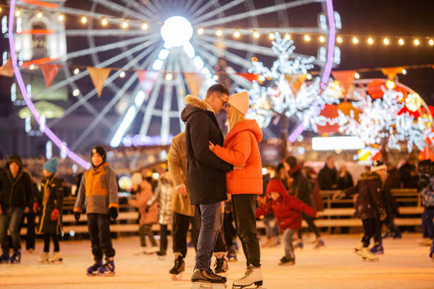 Couple in Love. Romantic Characters for Feast of Saint Valentine. True love. Happy Couple Having Fun at city ice rink in the evening. Happy romantic young couple enjoying together in skating-rink. - Фото, изображение