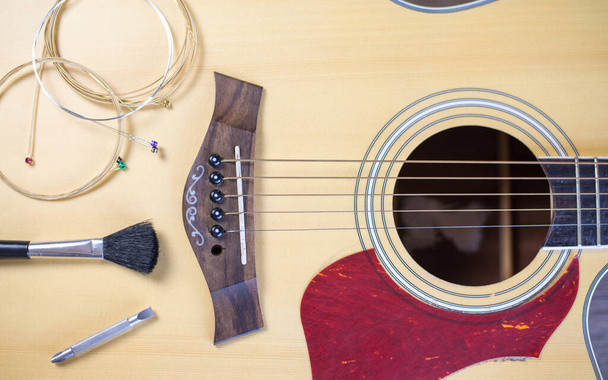 Pielęgnacja gitary akustycznej, struny gitarowe i narzędzia czyszczące umieszczone na gitarze, Widok z góry. - Zdjęcie, obraz