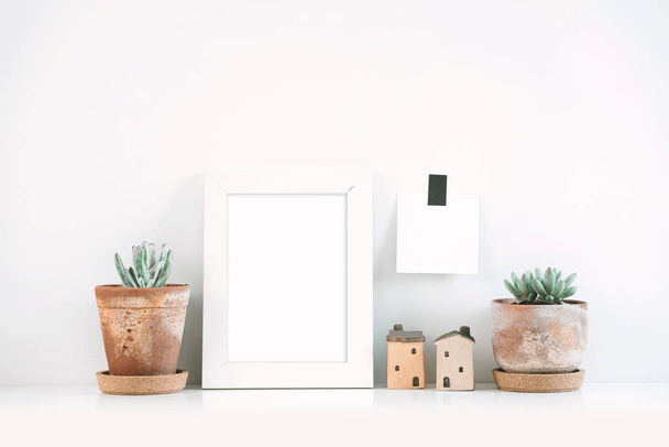 Succulents or cactus in clay pots over white background on the shelf and mock up frame photo. - Fotografie, Obrázek