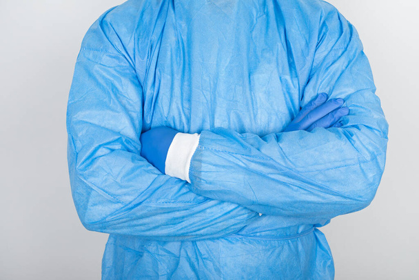 Young male doctor wearing surgical mask and protective scrubs on white background  - Foto, Imagem