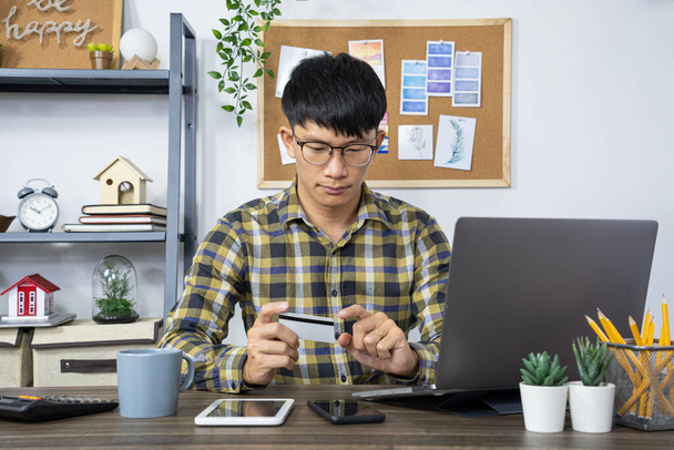 Aziatische man met credit card en het typen van informatie op internet met laptop thuis, online shopping concept - Foto, afbeelding