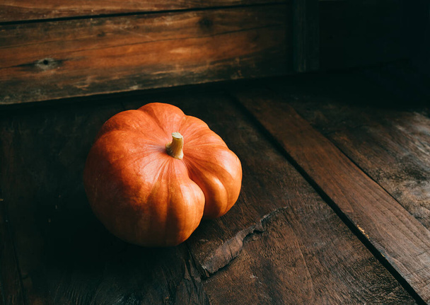 A fresh organic ripe pumpkin isolated on a dark wooden background. Harvesting - Fotó, kép