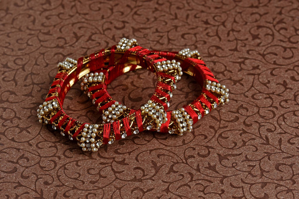Червоні кути Індії. Браслет з нитками, діамантами та перлами на текстурованому тлі, індійська традиційна ювелірна майстерня, стиль, мода та дизайн ювелірних виробів. - Фото, зображення