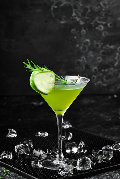 Green alcoholic cocktail with lime and rosemary. On a black stone background. Menu bar. - Foto, Imagen