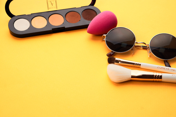 Luomivärejä keltaisella taustalla ammatillinen kosmetiikka meikki harjat pehmeä sieni muoti lasit - Valokuva, kuva