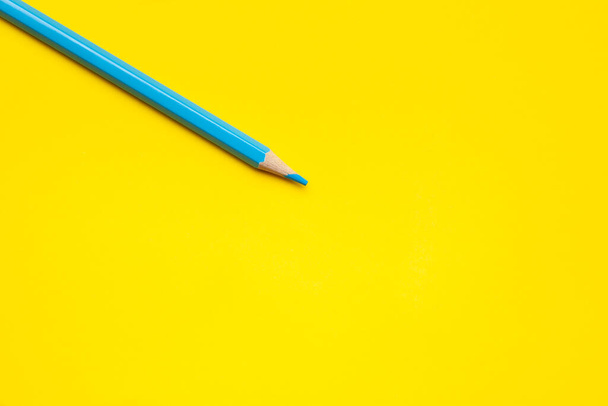 diagonal blue sharp wooden pencil on a bright yellow background, isolated, copy space, mock up - Φωτογραφία, εικόνα