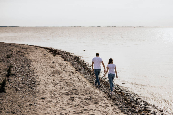 Romantic couple hold hands and walk on the beach. Travel vacation lifestyle concept - Fotoğraf, Görsel