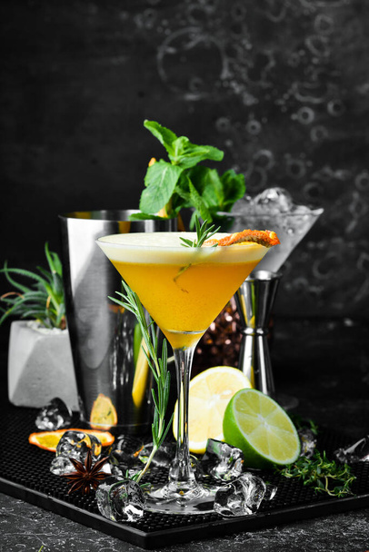 Alcoholic cocktail with sea buckthorn and orange with liqueur in a glass. On a black stone background. Menu bar. - 写真・画像