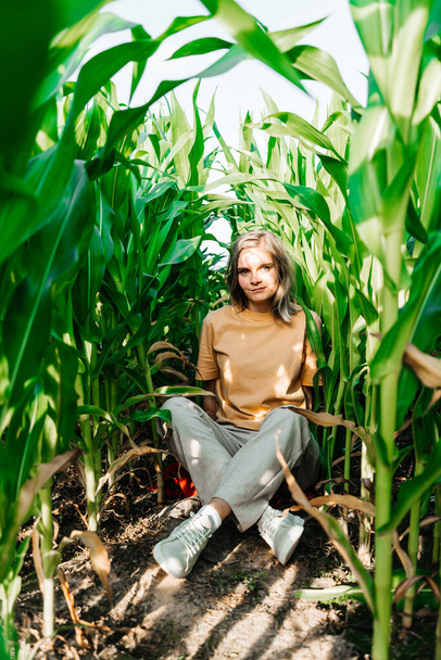 mujer joven en un campo de maíz en una camiseta amarilla con un lugar debajo del texto con pelo corto - Foto, Imagen