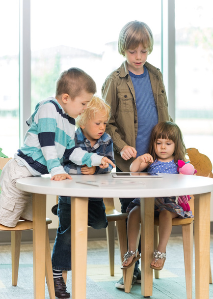 Enfants utilisant un ordinateur tablette au bureau dans la bibliothèque
 - Photo, image