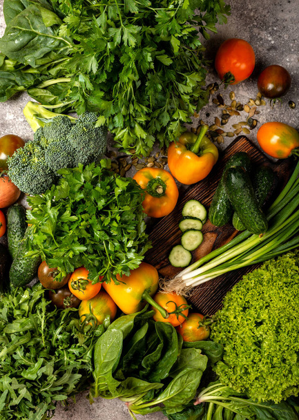 Świeże warzywa i zielenina z deską do siekania na stole. Zbliżenie - Zdjęcie, obraz