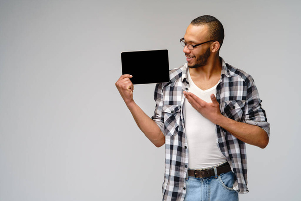 Portrait of a young african american man wearing green t-shirt holding tablet pc pad - Photo, Image