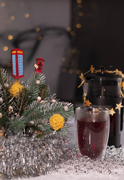 French press and tea in double-bottom glass near New Years decorations. Christmas theme - Photo, Image