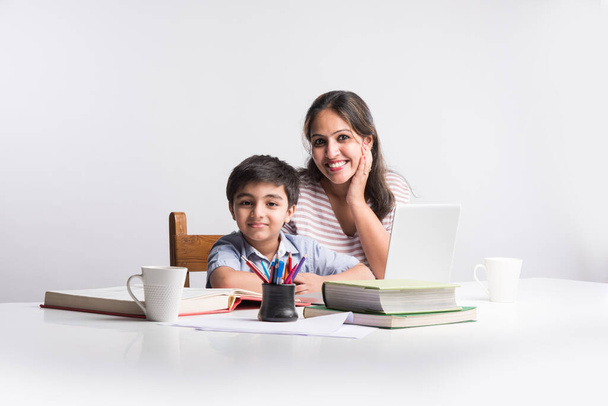 Roztomilý indický chlapec s matkou dělá domácí úkoly pomocí notebooku a knih - on-line školství koncept - Fotografie, Obrázek