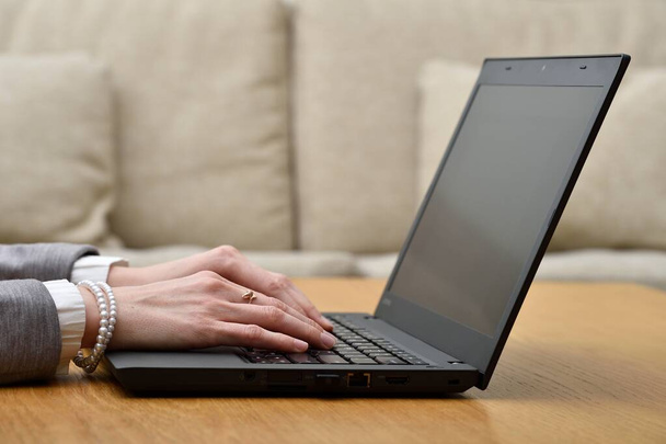 Mulher trabalhando em casa mãos de escritório no teclado de perto. Vista lateral de mulheres jovens mãos usando um laptop no interior da casa.  - Foto, Imagem