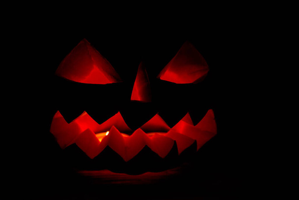 Spooky Halloween citrouille Jack-o-lanterne avec des bougies allumées sur fond sombre - Photo, image