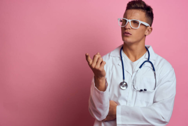 Arzt im Arztkittel mit Stethoskop um den Hals auf rosa Hintergrund und Brille im Gesicht - Foto, Bild