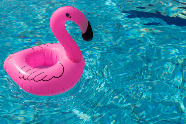Flamingo geïsoleerd. Roze opblaasbare flamingo in zwembadwater voor zomerse strand achtergrond. Zwembad float party - Foto, afbeelding