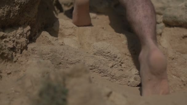Ember séta mezítláb a homokon sziklák, mászás és séta szabadtéri lassított felvétel. Alacsony szögű lövés. Valós városi menekülési koncepció - Felvétel, videó