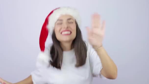 Young beautiful woman wearing Santa Claus hat over isolated white background very happy, dancing very energetic - Imágenes, Vídeo