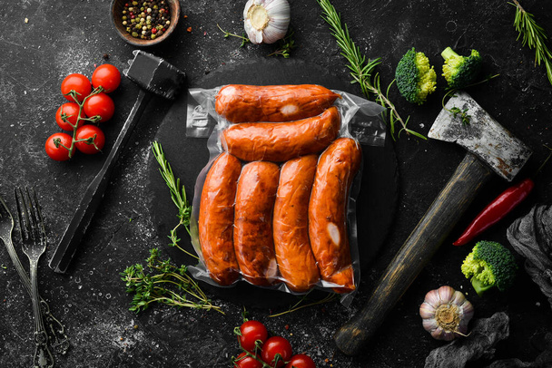 Smoked sausages in vacuum packaging. Top view. On a black background. - Foto, afbeelding