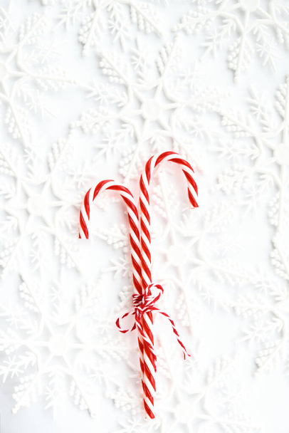 Christmas Candy canes with striped rope bow on white background with snowflakes. Sweet Christmas Card - Photo, Image