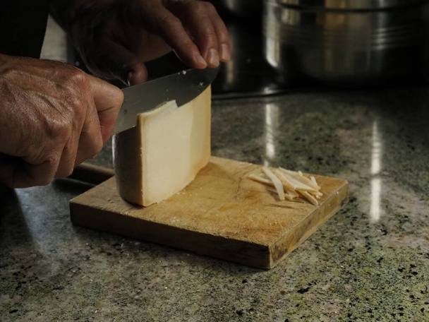 Mani di un uomo che taglia un formaggio idiazabal - Foto, immagini