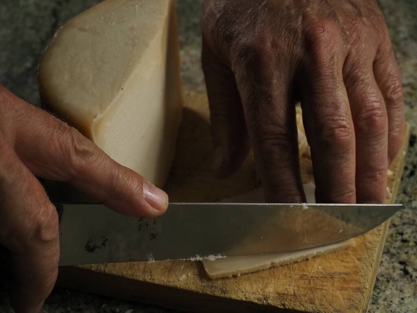 Mãos de um homem cortando um queijo Idiazabal - Foto, Imagem