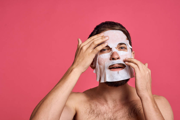 man in cleansing mask on pink background gesturing with hands naked torso cropped view - Foto, afbeelding
