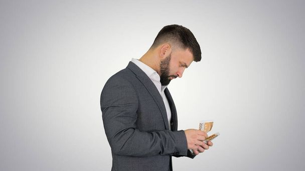 Happy and satisfied businessman counting euros on gradient backg - Photo, image