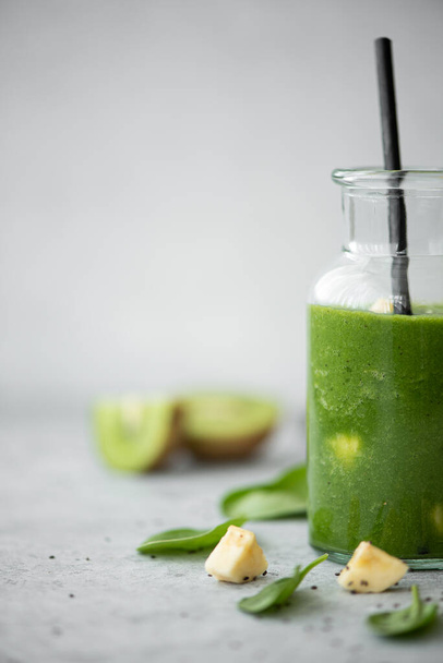 green spinach, banana and kiwi smoothie with chia seeds and small bottles on a grey table - Fotó, kép