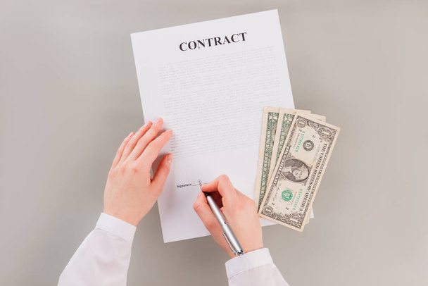 Женщина подписывает контракт, чтобы получить много денег. - Фото, изображение
