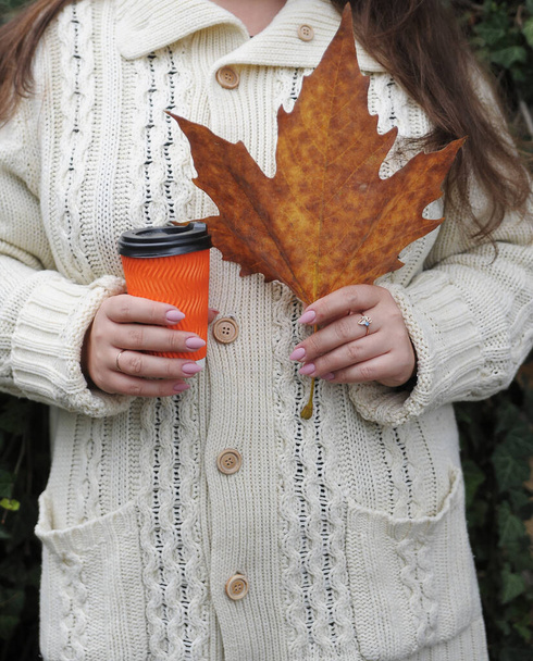 Hand with cup of coffee on autumn background. - Foto, Bild