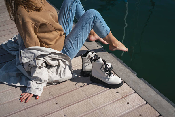 Девушка в белых туфлях сидит на пирсе яхт-клуба, читает газету и отдыхает. новая коллекция обуви осень зима 20 / 21 фото моды Любек, Германия сентябрь 2020 - Фото, изображение
