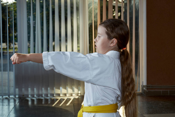 With a yellow belt, a beautiful athlete trains a punch - Photo, Image