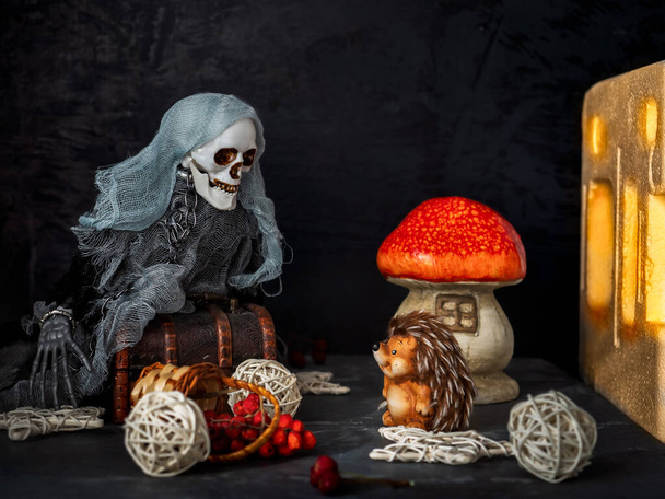 Postcard with Halloween, skeleton and hedgehog are talking, rowan berries and apples on a dark background - Photo, Image