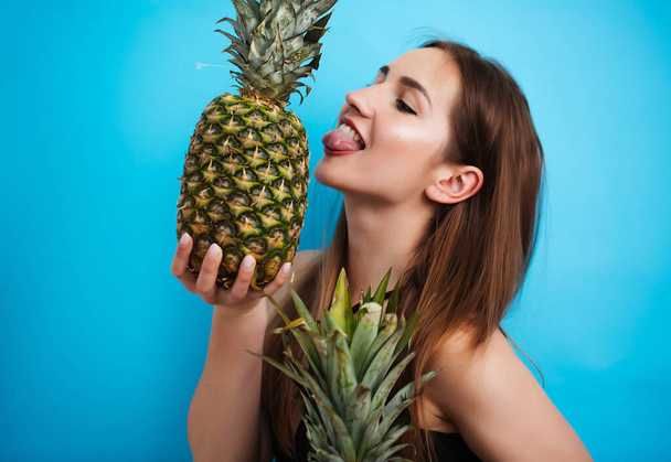 Portrait of young woman in swimsuit with pineapple on blue background. Summer season - Fotó, kép