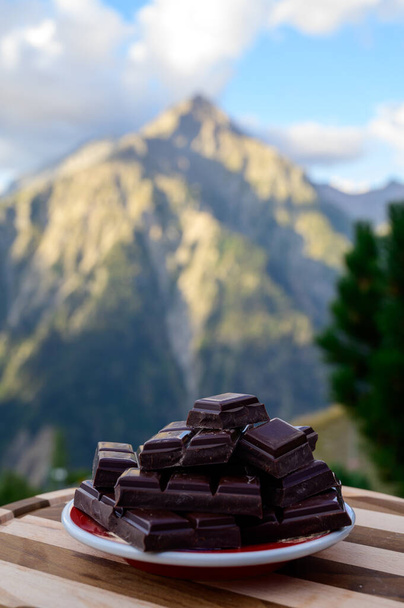 Kézzel készített tiszta sötét svájci csokoládé és alpesi hegyek a háttérben nyáron - Fotó, kép