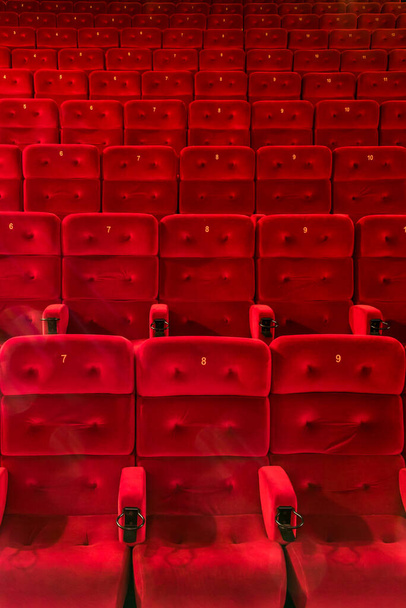 Sièges rouges confortables vides avec des numéros dans le hall du cinéma ou du théâtre - Photo, image