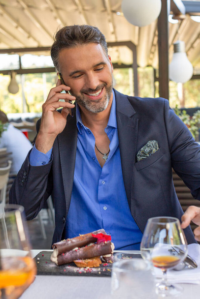 Handsome man talking on the a smartphone in the restaurant - Photo, Image
