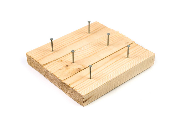 Demonstration of metal nails driven into wooden boards on a white background. - Photo, Image