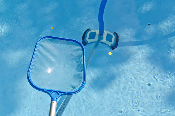 καθαρισμός λεκάνης κολύμβησης με δίχτυ βυθίσεως και ηλεκτρική σκούπα πισίνας - Φωτογραφία, εικόνα